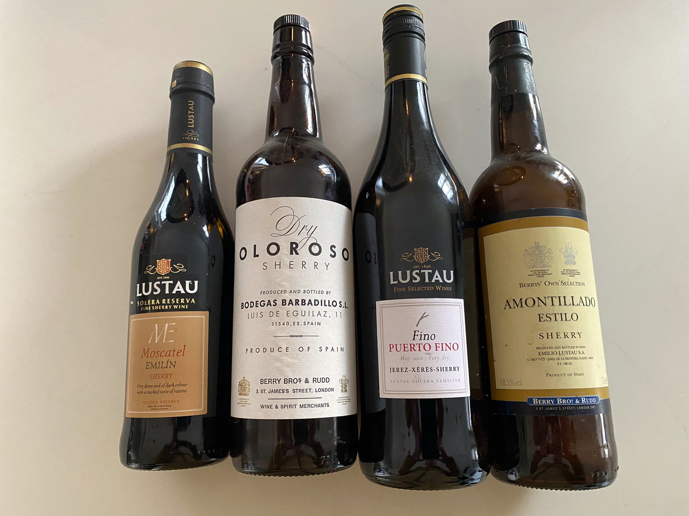Four bottles of sherry standing side by side: a sweet moscatel, a dry oloroso, a fino and an amontillado.